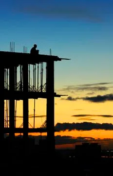 Lonely construction worker sitting at the edge of unfinished house floor, med Stock Photos