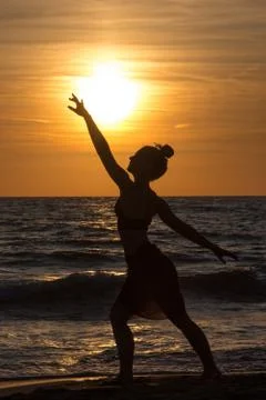 Lonely Dancer ballet posing on the beach sunset silhouette sea Stock Photos