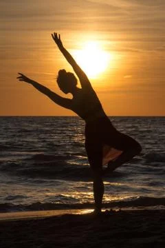 Lonely Dancer ballet posing on the beach sunset silhouette sea Stock Photos