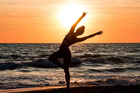 Lonely Dancer ballet posing on the beach sunset silhouette sea Stock Photos