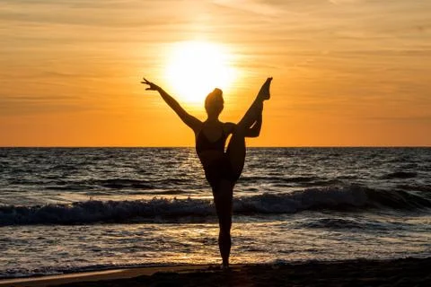Lonely Dancer ballet posing on the beach sunset silhouette sea Stock Photos