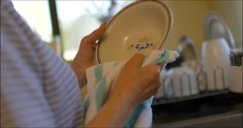 Lonely elderly lady dries dishes in her kitchen. Vidéo 88368626