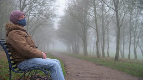 Lonely Elderly Man Wearing Mask Sits Alone in Park Mid Shot Stock Footage 147901997