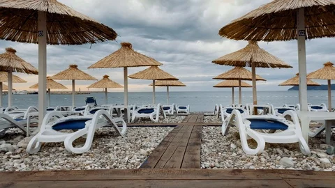 Lonely, empty beach with plastic sunbeds and palm umbrellas at Montenegro Stock Footage 119640239