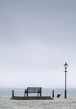 Lonely empty bench in open tranquil landscape by the sea for mindfulness and Stock Photos