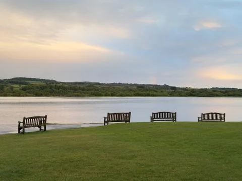 Lonely empty seats in open tranquil landscape by the lake for mindfulness and Stock Photos