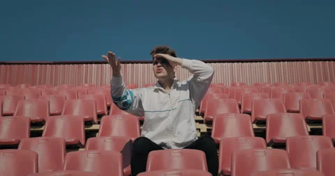 A lonely fan at a sporting event in an empty stadium on a sunny day. 库存影片 152971514