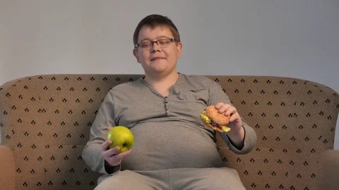 Lonely fat guy eating hamburger. 4K UHD Stock Footage 73516492