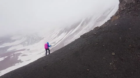 Lonely female backpacker dressed rain cover with backpack and trekking poles mak Video stock 329763718