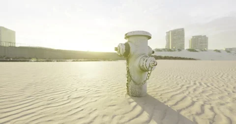 Lonely fire hydrant standing tall against the sandy beach at sunset Stock Footage 318066832