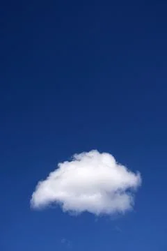 Lonely fluffy white cloud in deep blue sky Stock Photos