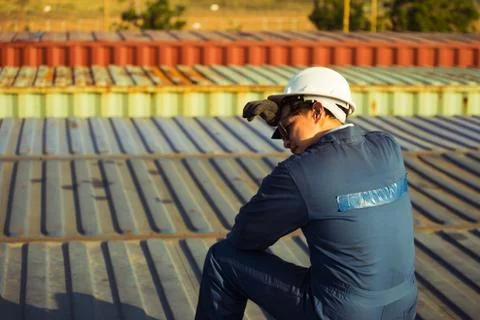 Lonely Foreman worker lost in depression on the containers box in the cargo Фото