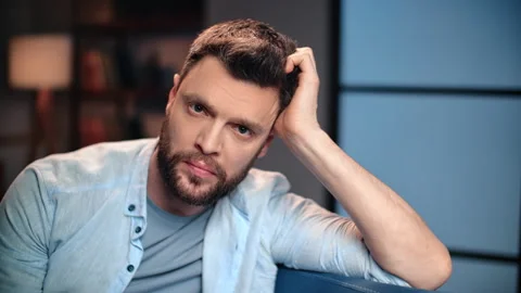 Lonely frustrated man looking at camera and learning head on arm, sitting alone Stock Footage 279769811