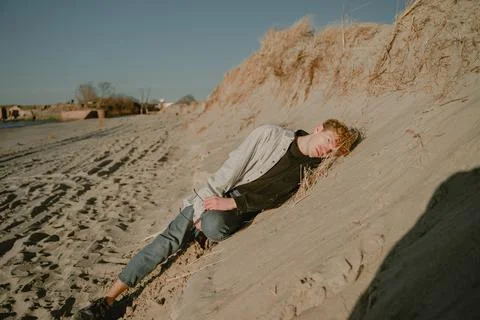 Lonely guy lying on the sand looking at the camera Stock Photos
