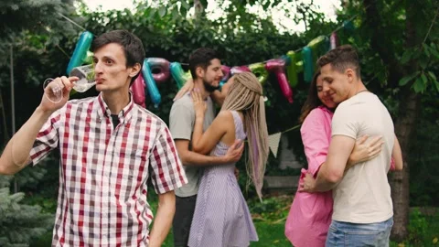 A lonely guy standing at the edge of a birthday party, sipping champagne while Stock Footage 286896491