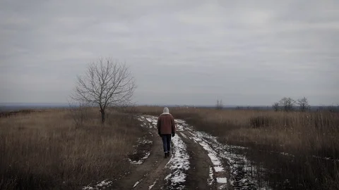 A lonely guy walking along a winter field. Stock Footage 124480673