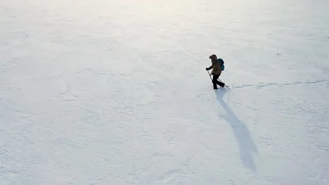 Lonely hiker in down jacket with backpack and ski poles walk through snow - Stock Footage 198645832