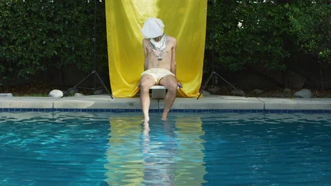 Lonely hipster man sits on diving board at pool with bag over his head Stock Footage 108942263