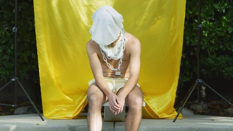 Lonely hipster man sits on diving board at pool with bag over his head Stock Footage 108943002