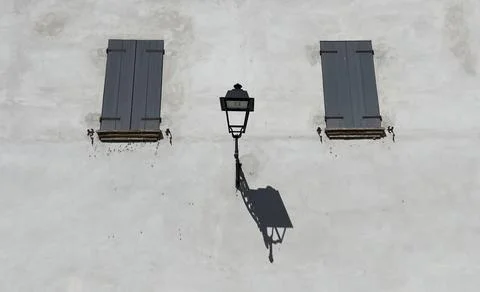 A lonely lantern on the wall between two windows Stock Photos