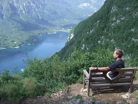 Lonely man admiring mountain landscape while sitting on bench Stock Photos