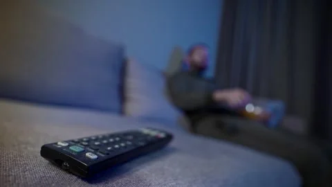 Lonely man enjoying snacks while sitting on a couch and watching TV. Stock Footage 313402748