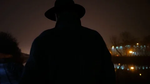 Lonely man with hat and coat walking at night city with river Stock Footage