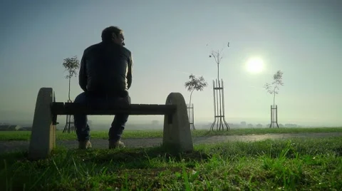 Lonely man looking for a hope. Staring at the sun. A Beautiful woman passes by.  Stock Footage 68329712