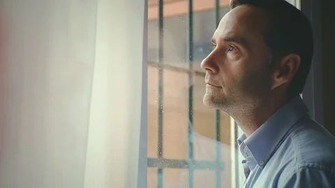 Lonely Man Looking Through Window At Home Stock Footage