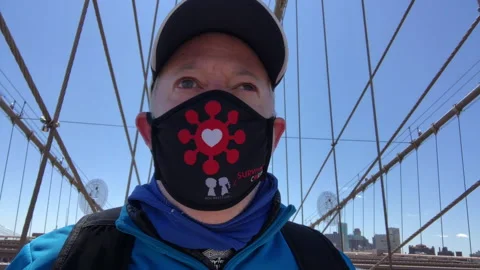 Lonely Man with mask runs across empty Brooklyn Bridge, NYC Stock Footage