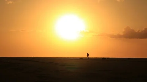 Lonely man on sandy beach under big sun Stock Footage 86387363