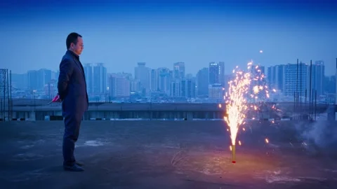 A lonely man is setting off fireworks on the rooftop at night Stock Footage 325541867