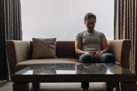 Lonely man sits on the sofa thinking of his lover. Stock Photos