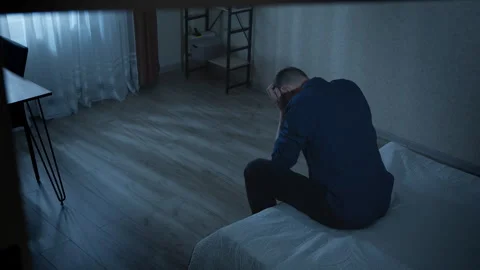 Lonely man sitting on bed in dark room. Depression, problems, stress and sadness Stock Footage 303910137