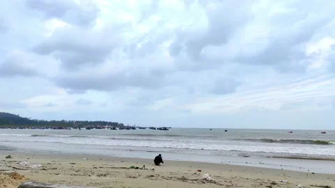Lonely man sitting on the winter cloudy beach, orbit shot Video stock 146250963