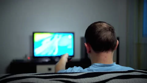 Lonely man spends the evening at the TV, rear view, camera movement Stock Footage 132355702