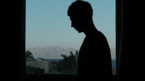 Lonely man standing by window after breakup, lost in thought Video stock 347302656