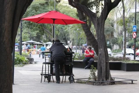 Lonely man under the red umbrella on the mexican street Stock Photos