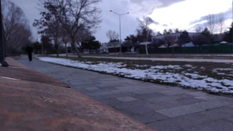 A lonely man walking along a stone path in a gloomy park during twilight, Vídeos de archivo 333525397