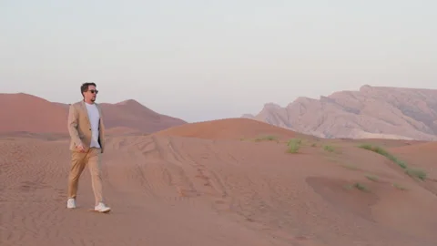 Lonely man walking in empty lifeless desert, strolling on sand dunes in sunset 스톡 동영상 263377685