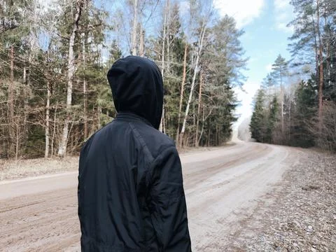 Lonely man is walking on a forest path a hoodie. mental health concept. Stock Photos