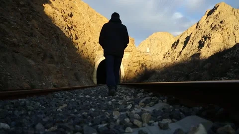 Lonely man walking towards a train tunnel Stock Footage 241706171