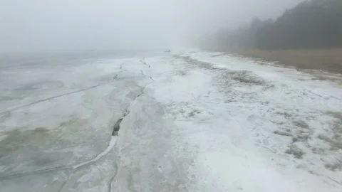 Lonely man walks through snow and ice of frozen sea coastline Stock Footage 91794876