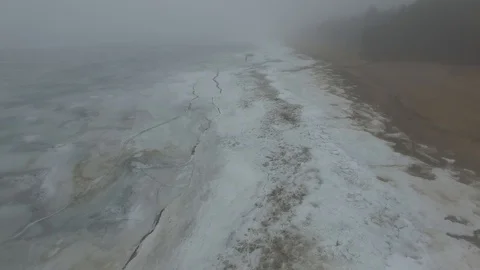 Lonely man walks through snow and ice of frozen sea coastline Stock Footage 91796344