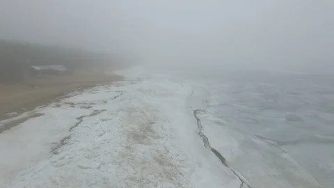 Lonely man walks through snow and ice of frozen sea coastline Stock Footage 91797891