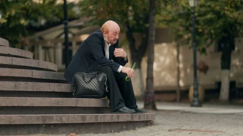 Lonely office worker drinking alcohol on city stairs after work Stock Footage 318879574