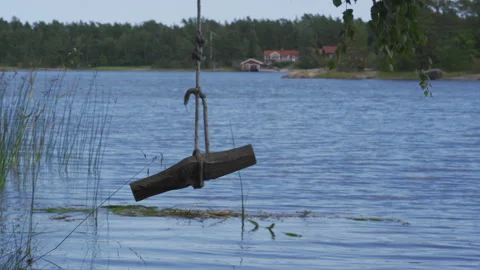A lonely old empty wooden swing above the water in a lake Stock Footage 159094497