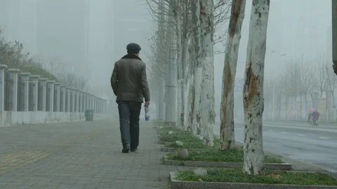 A lonely old man walks on the road on a cloudy day_01 Stock Footage 240643299