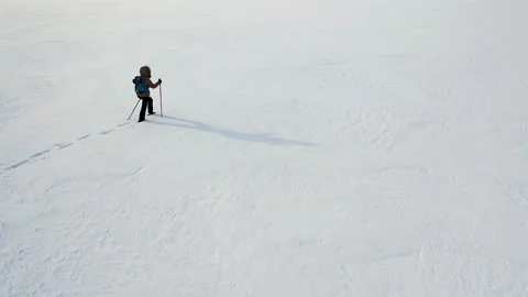 Lonely person in winter clothes with backpack and ski poles walks through Stock Footage 200395253
