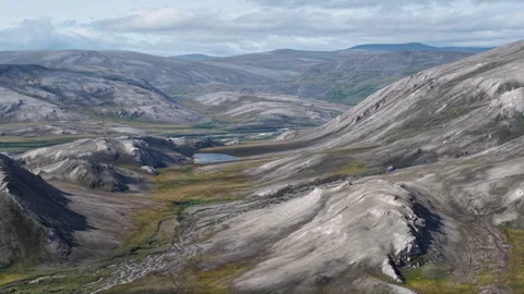 Lonely pyramidal mountain beside green river in Lavrentiya Bay Chukotka Stock Footage 327123997